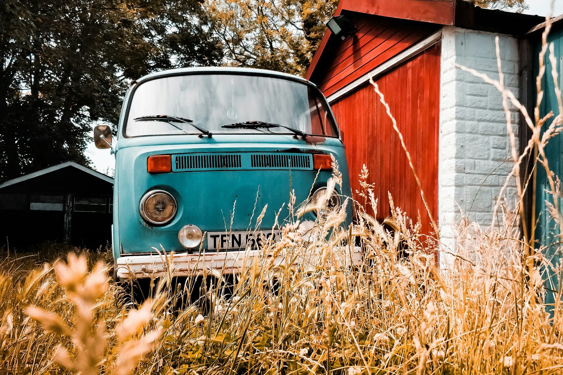 An image of a rad old van hiding behind a barn. Photo credit: Matthew Foulds via Unsplash.com.